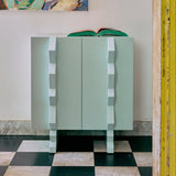 Modern blue cabinet against a white wall with a colorful painting of four people above it.