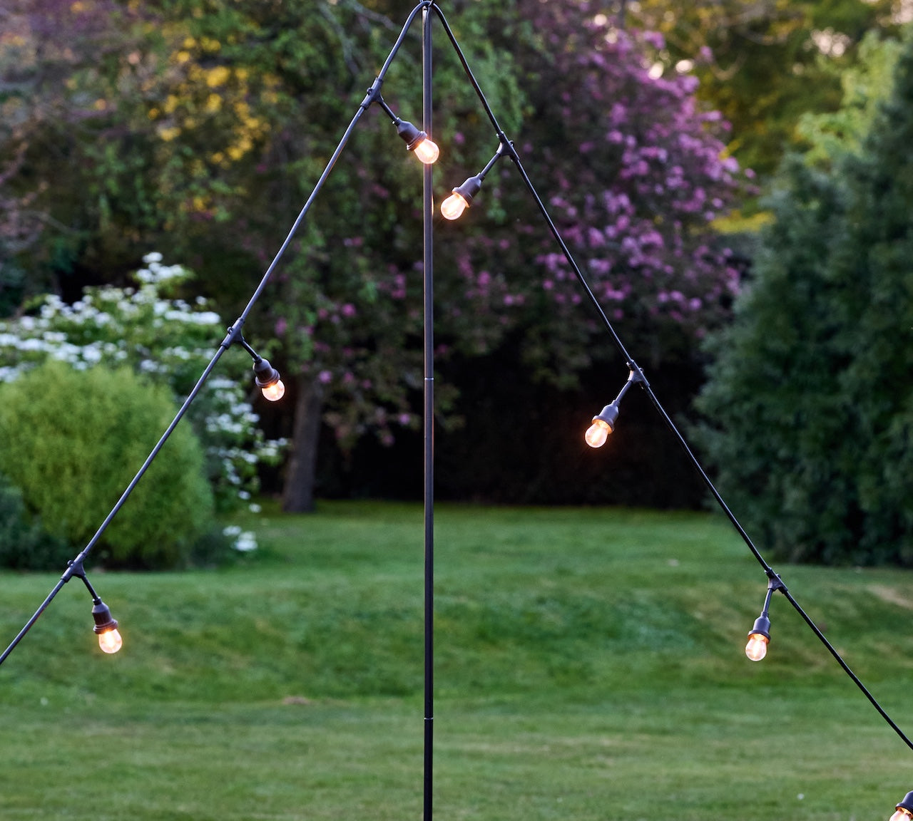String lights hanging from a metal stand in a garden setting