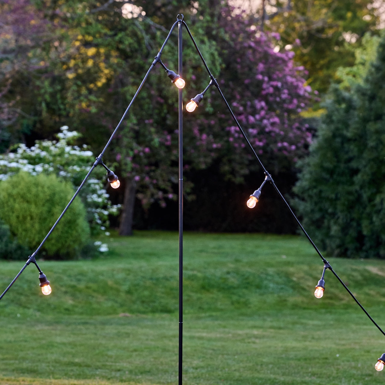 String lights hanging from a metal stand in a garden setting