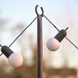 String lights with white bulbs and black holders on a blurred outdoor background