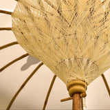Close-up of a traditional woven umbrella with a geometric pattern on a plain background