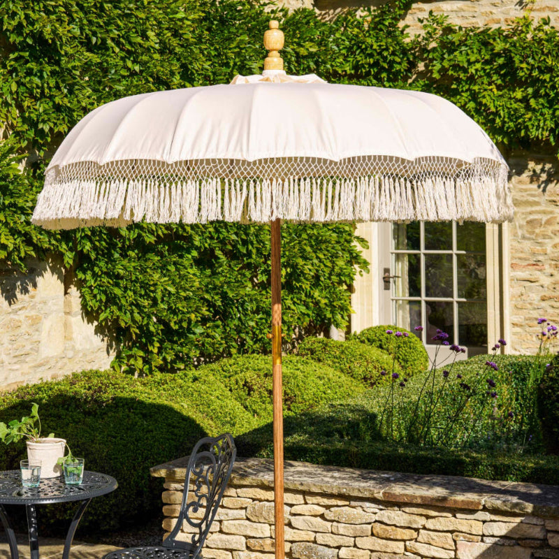 Decorative outdoor umbrella with fringe in a garden setting
