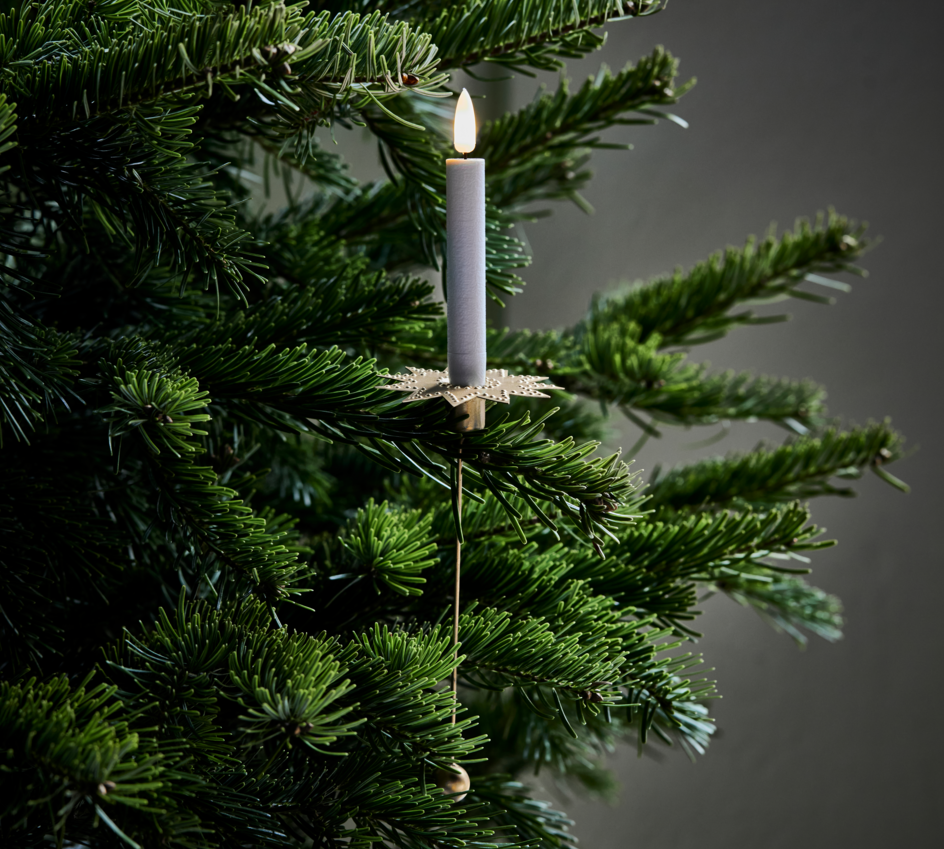 Decorative candle hanging on a Christmas tree against a dark background