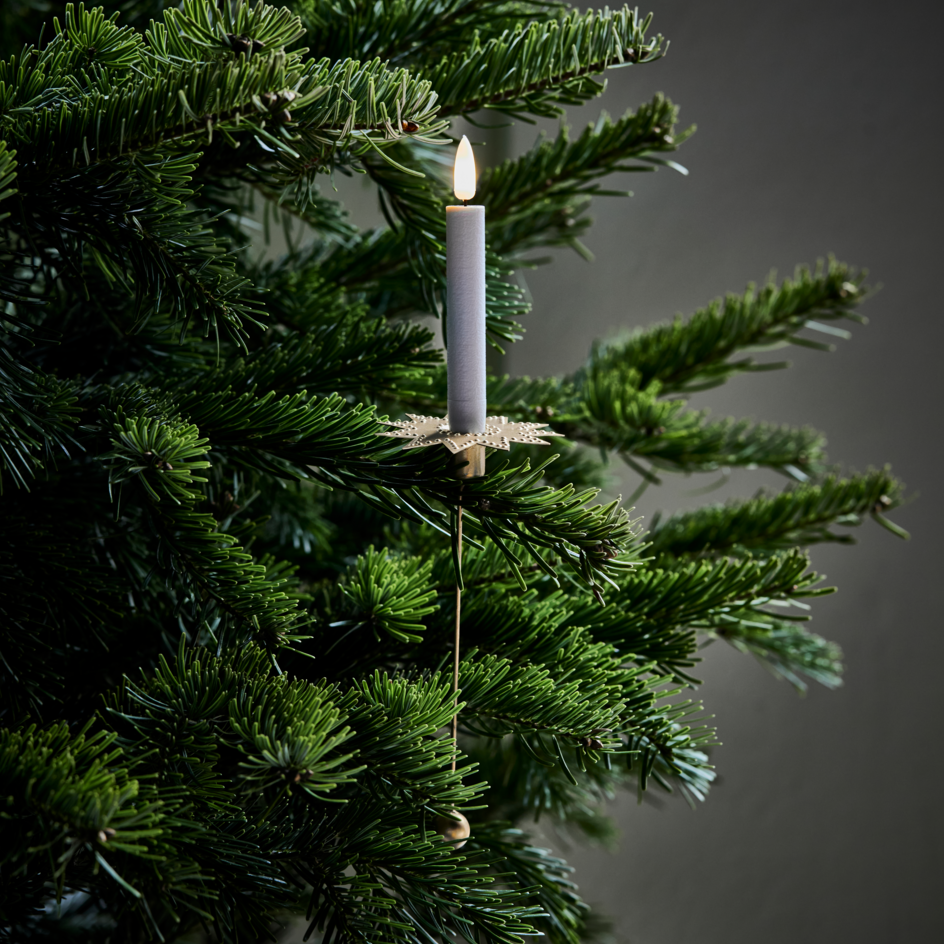 Decorative candle hanging on a Christmas tree against a dark background