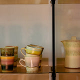 Stack of ceramic mugs with a pitcher on a reflective surface