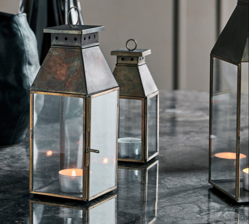 Decorative lanterns with candles on a reflective surface