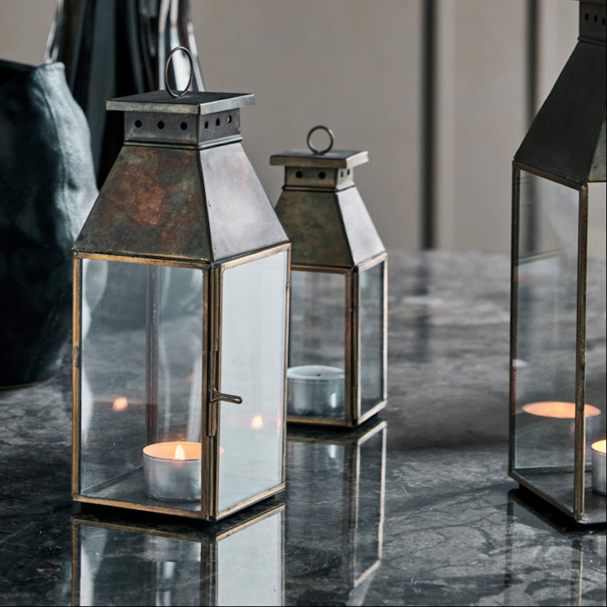 Decorative lanterns with candles on a reflective surface