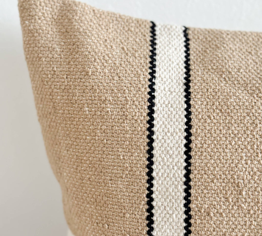 Textured pillow with a black and white stripe on a neutral background