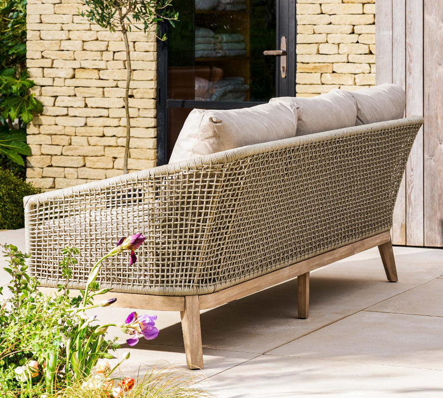 rattan outdoor sofa with cushions on a patio area.