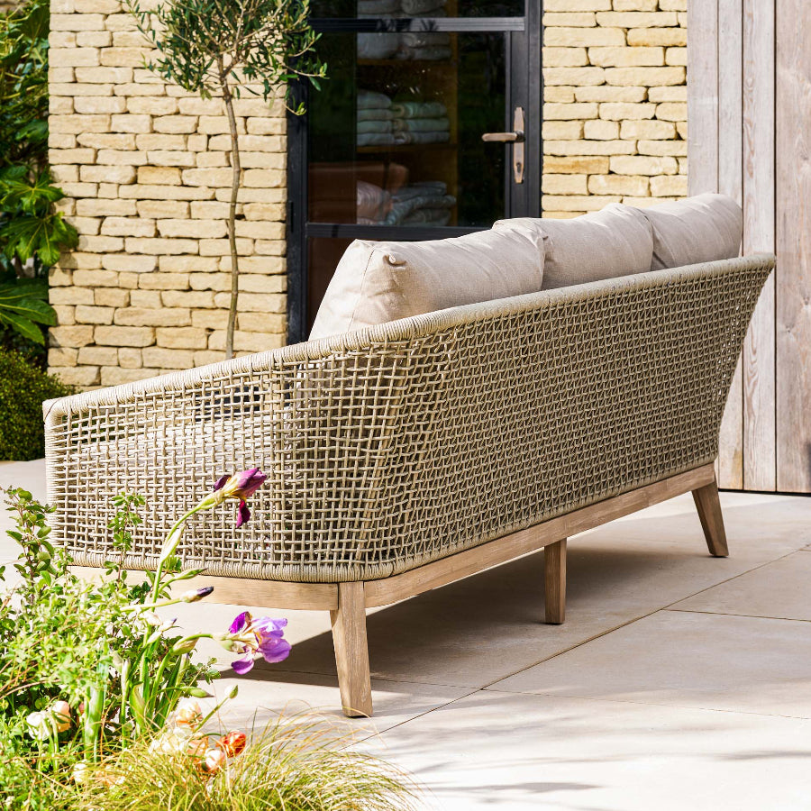 rattan outdoor sofa with cushions on a patio area.