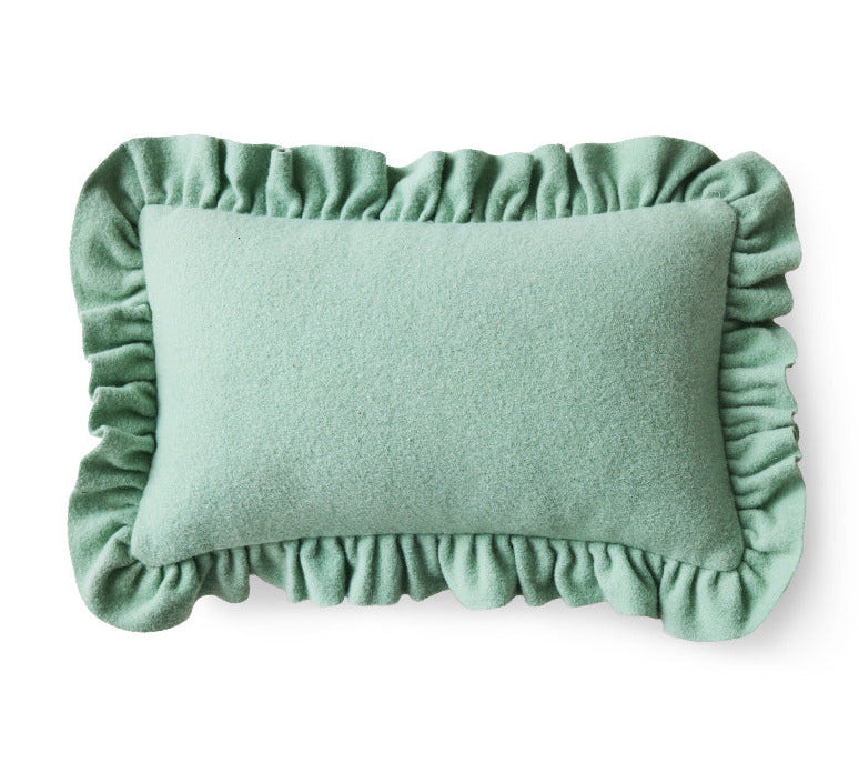 Green cushion with ruffled edges on a white background