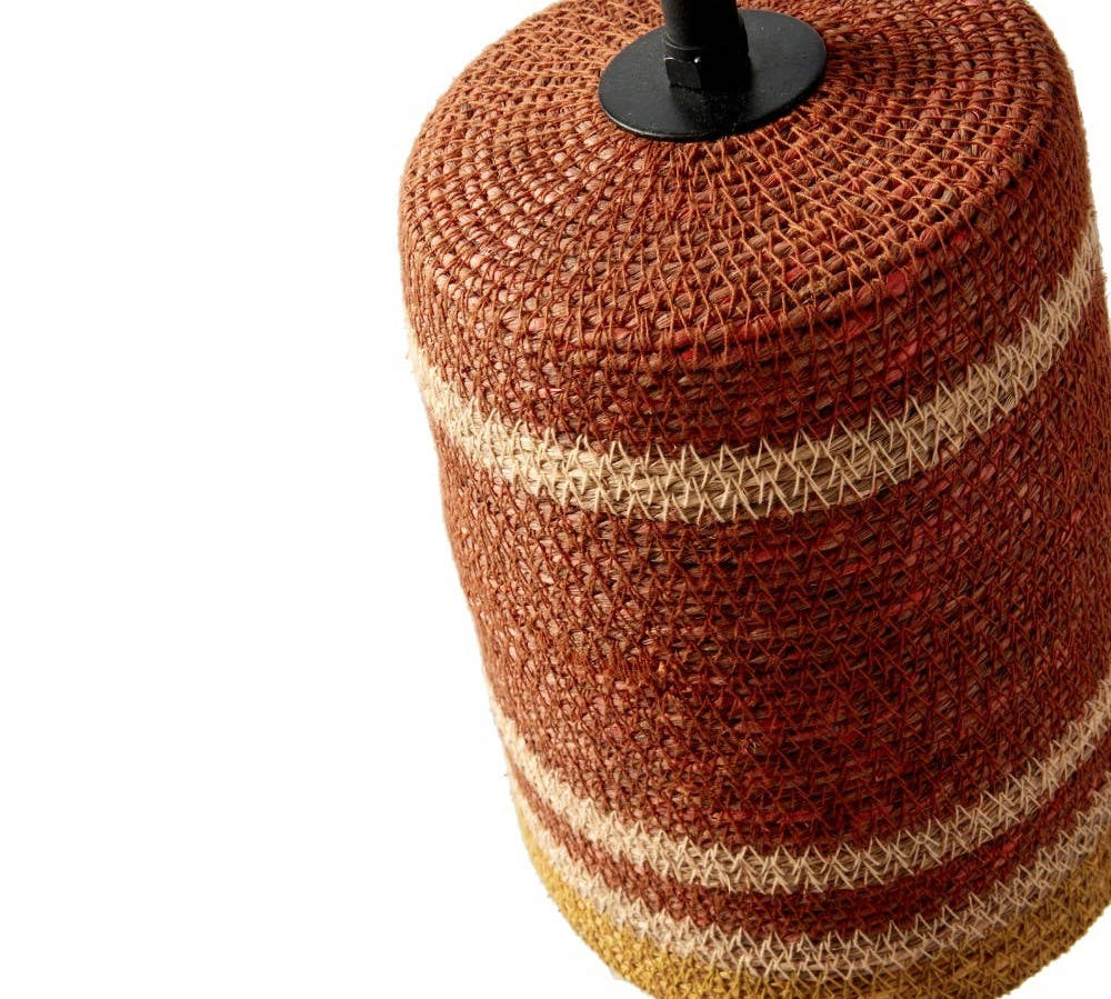 A woven cylindrical lampshade or decorative pot cover in a rust red and beige striped pattern, shown on a white background with a black top finial visible.