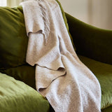 Beige blanket draped over a green sofa with a blurred background