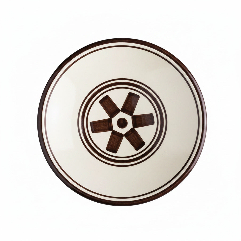 Ceramic plate with brown rim and decorative center on a white background