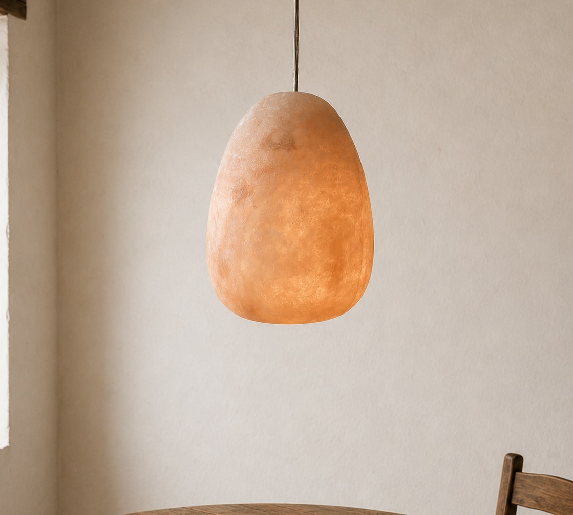 Round wooden table with a pendant light fixture against a neutral wall.