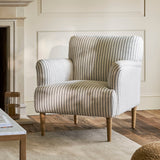 Striped armchair in a living room setting with wooden floor and fireplace.