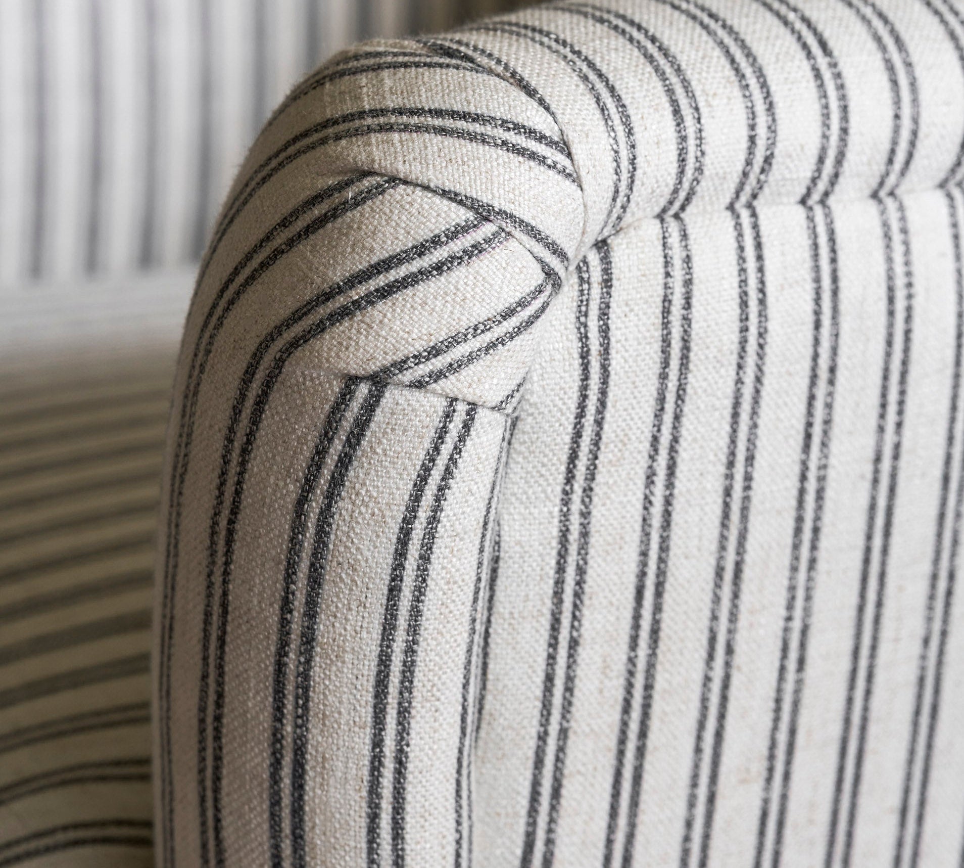 Close-up of a striped fabric armchair with a neutral color palette.