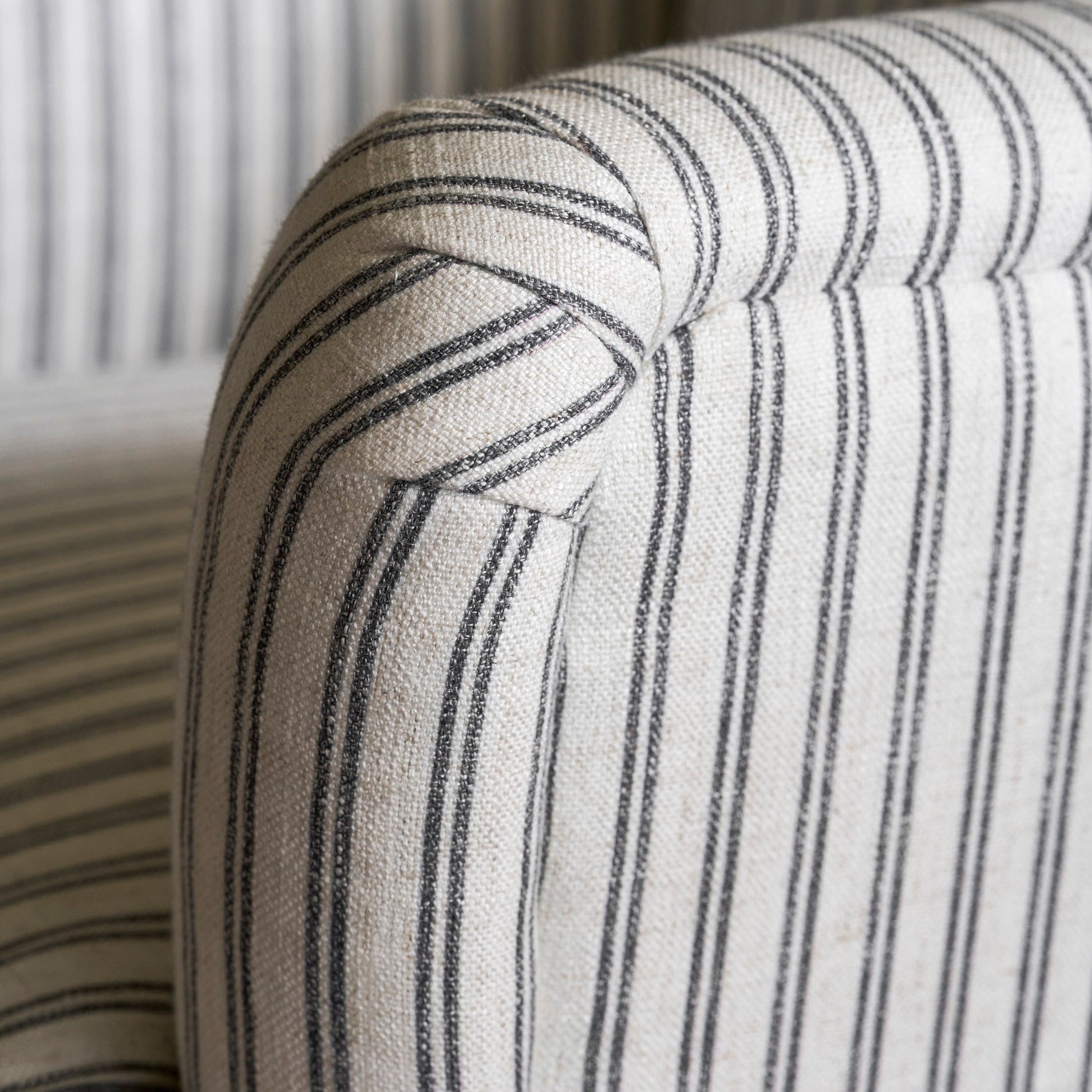 Close-up of a striped fabric armchair with a neutral color palette.