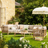 Outdoor Porthallow corner sofa with wooden furniture, umbrella, and plants in a garden setting.