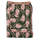 A folded quilted blanket featuring a dark green background with a repeating pattern of pink and white stylized cats, finished with a striped orange and white border.