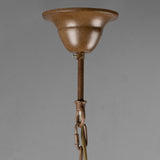 Close-up of a hanging ceiling fixture canopy and downrod in a warm metallic bronze finish, shown against a plain gray studio background.