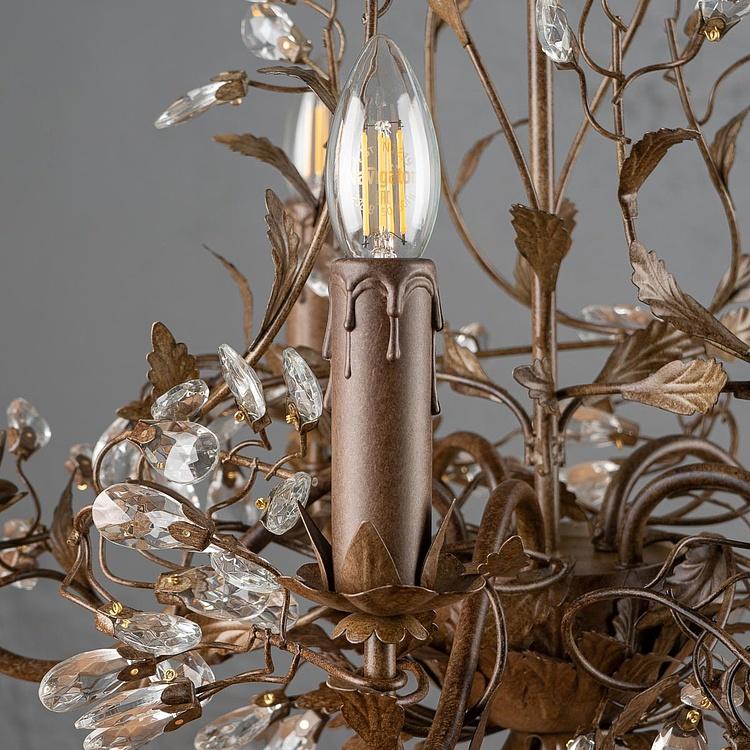 Close-up of a decorative chandelier with a bronze-finished metal frame, leaf and vine details, clear teardrop crystal drops, and a candle-style bulb with a visible filament.