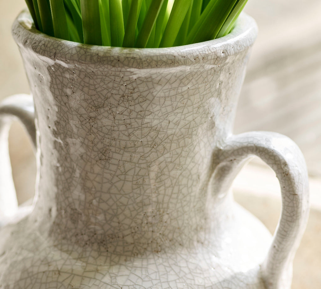 White textured vase with green plant on a light background