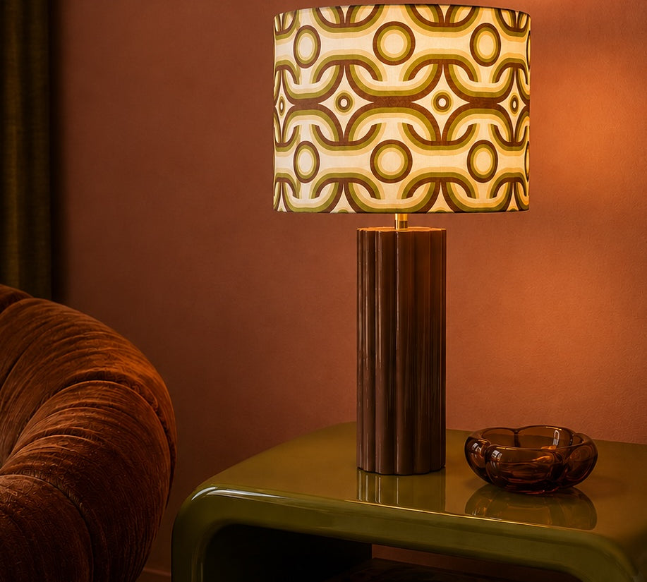 Decorative retro lamp with a patterned shade on a table against a warm-toned wall