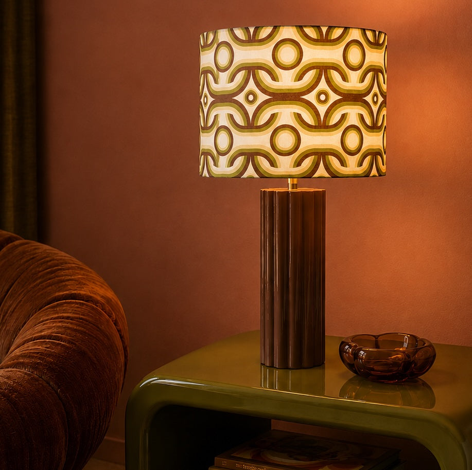 Decorative retro lamp with a patterned shade on a table against a warm-toned wall