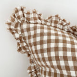 Brown and white checkered fabric with ruffled edges on a light gray background
