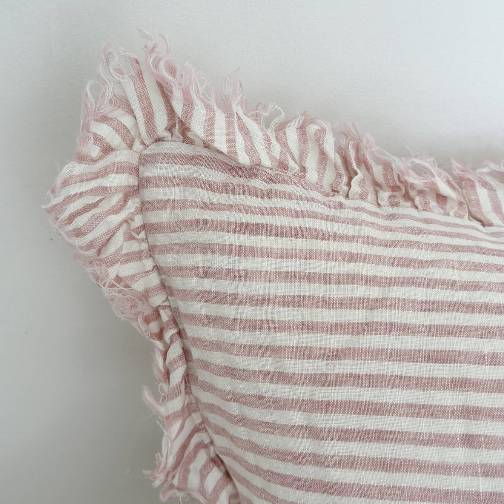 Close-up of a pink and white striped fabric with ruffled edge on a light background