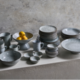 Set of grey ceramic crockery on a concrete surface 
