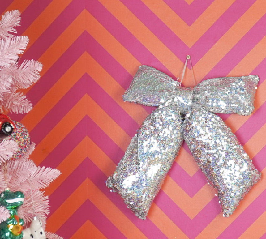Decorative pink Christmas tree with ornaments against a pink and orange chevron patterned wall.