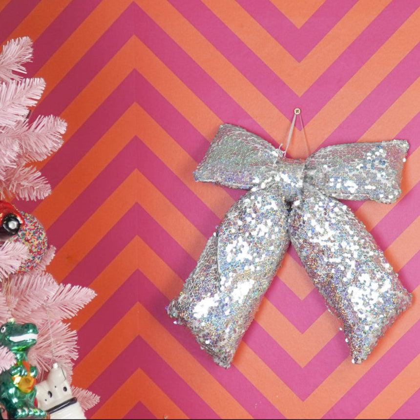 Decorative pink Christmas tree with ornaments against a pink and orange chevron patterned wall.