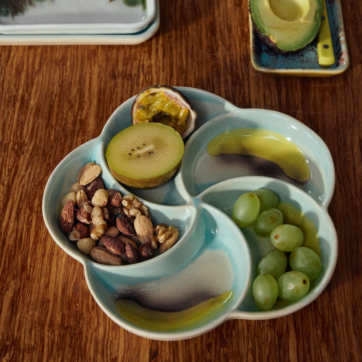 Snack platter on a wooden table with additional fruits in the background.