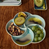 Snack platter on a wooden table with additional fruits in the background.
