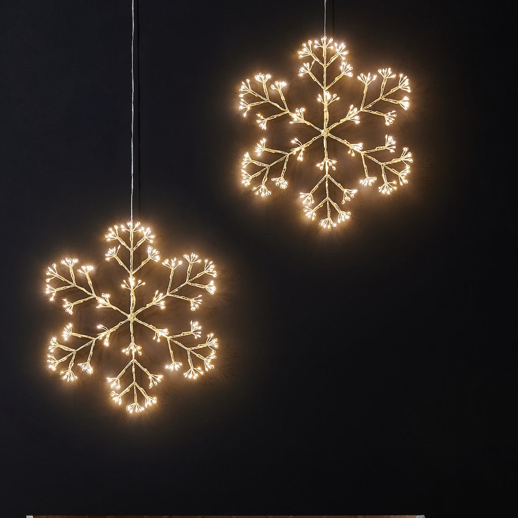 Two illuminated snowflake-shaped lights against a black background