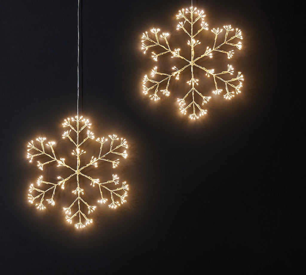 Two illuminated snowflake-shaped lights against a black background