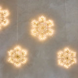 Decorative string lights shaped like snowflakes on a textured wall.