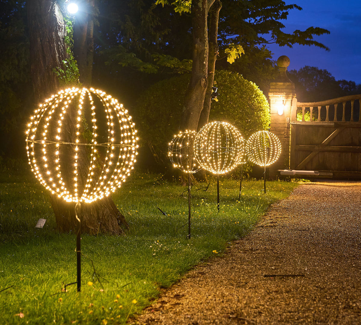 Decorative outdoor lights shaped like spheres on a grassy area at night.