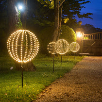Decorative outdoor lights shaped like spheres on a grassy area at night.