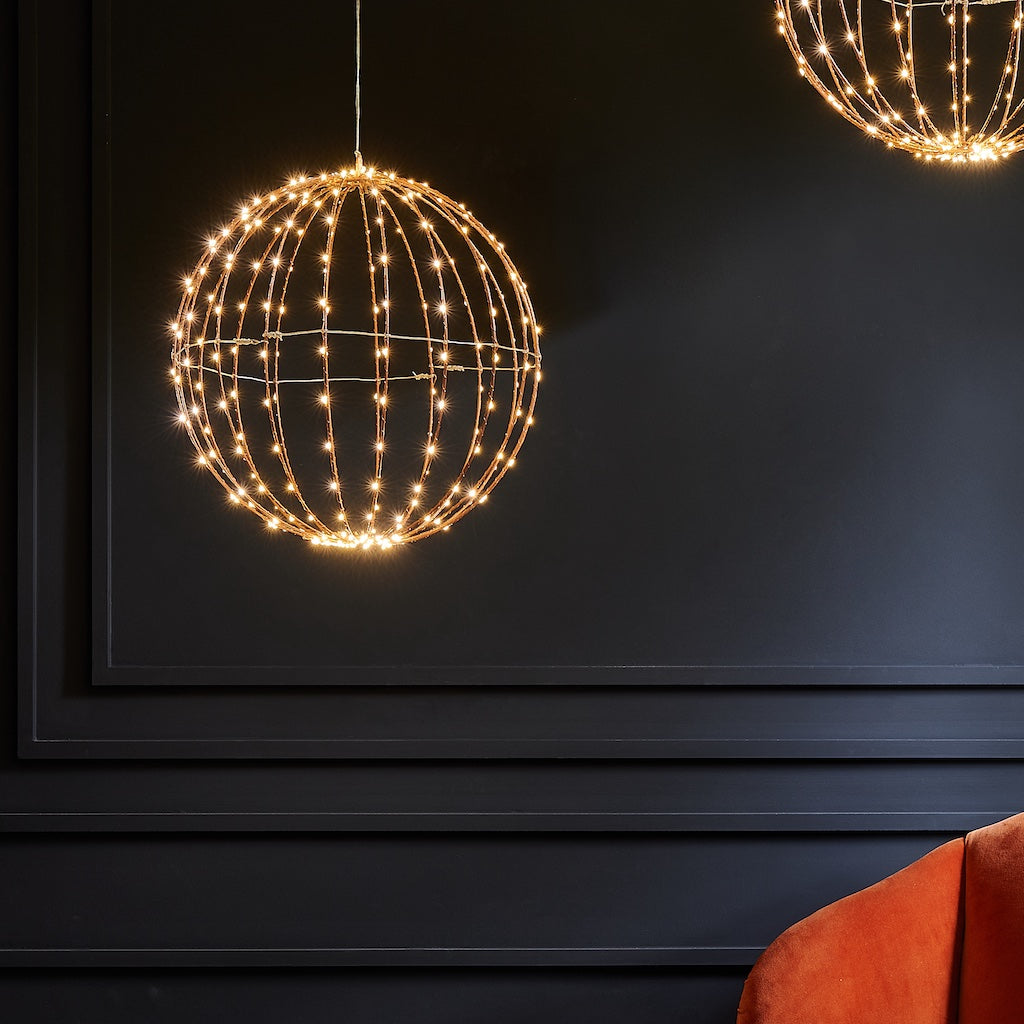 Decorative copper sphere LED lights hanging against a dark wall 