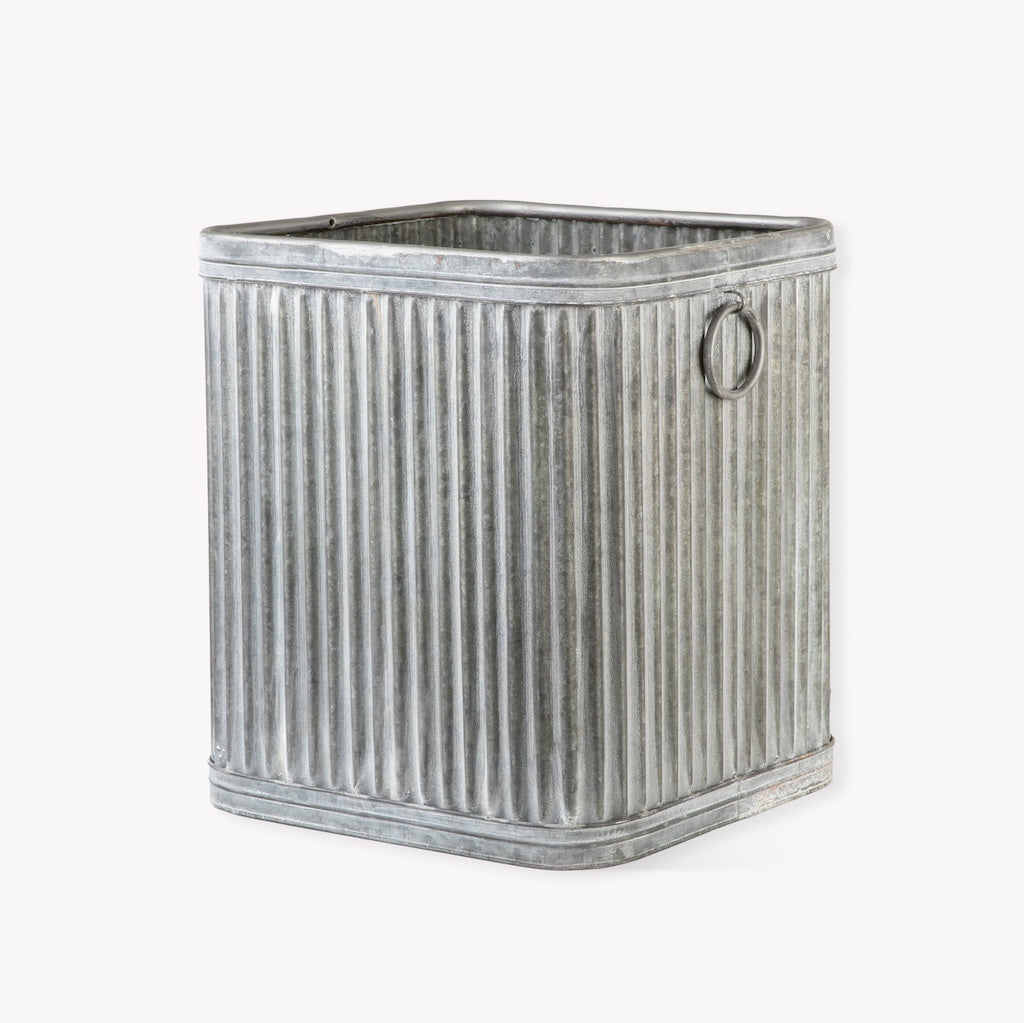 Metallic ribbed storage bin with a handle on a white background