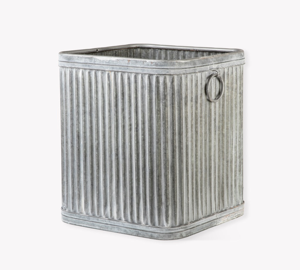 Metallic ribbed storage bin with a handle on a white background