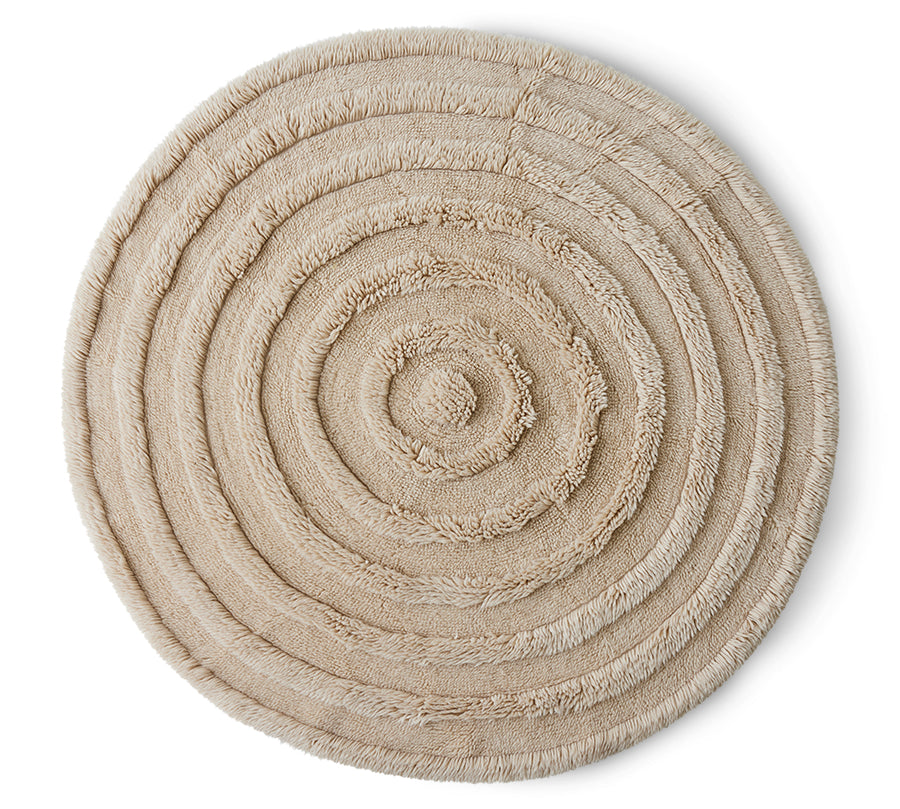 A round wool rug in cream color with a textured pattern.