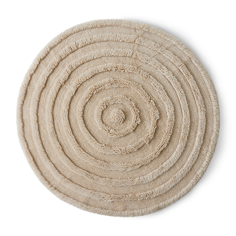 A round wool rug in cream color with a textured pattern.