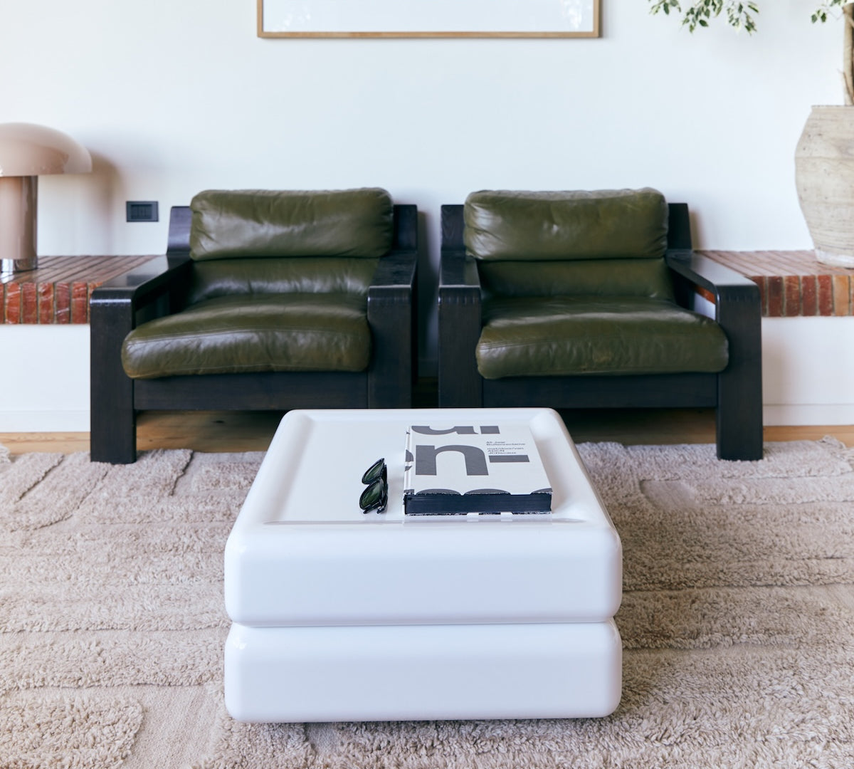 Tufted fluffy beige rug withe a modern white coffee table and retro chairs