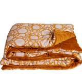 Folded orange and white floral patterned blanket on a white background