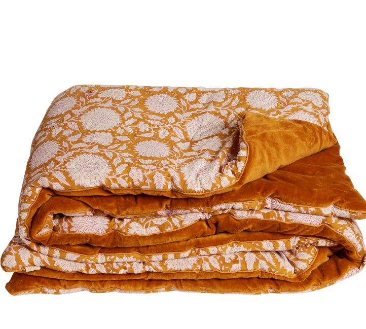 Folded orange and white floral patterned blanket on a white background