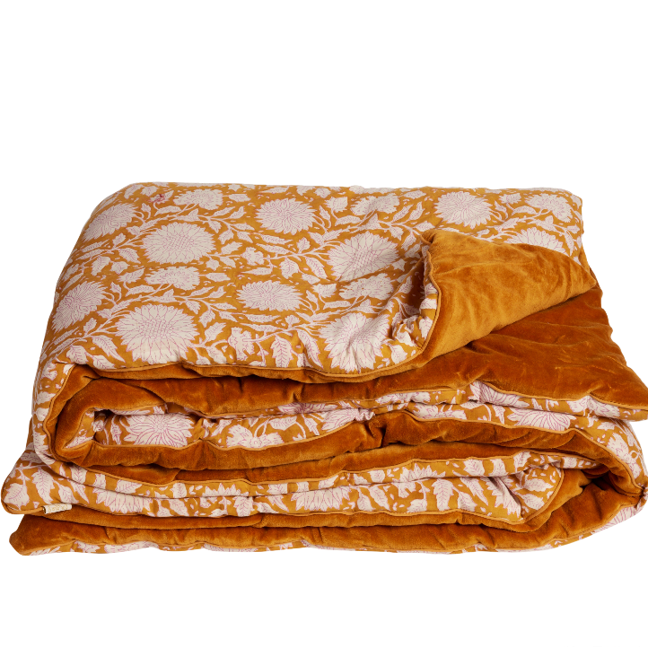 Folded orange and white floral patterned blanket on a white background